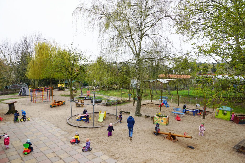 Blick von oben auf den Außenbereich der Kita Regenbogen. Aus der Vogelperspektive wird die Weitläufigkeit des Geländes deutlich.