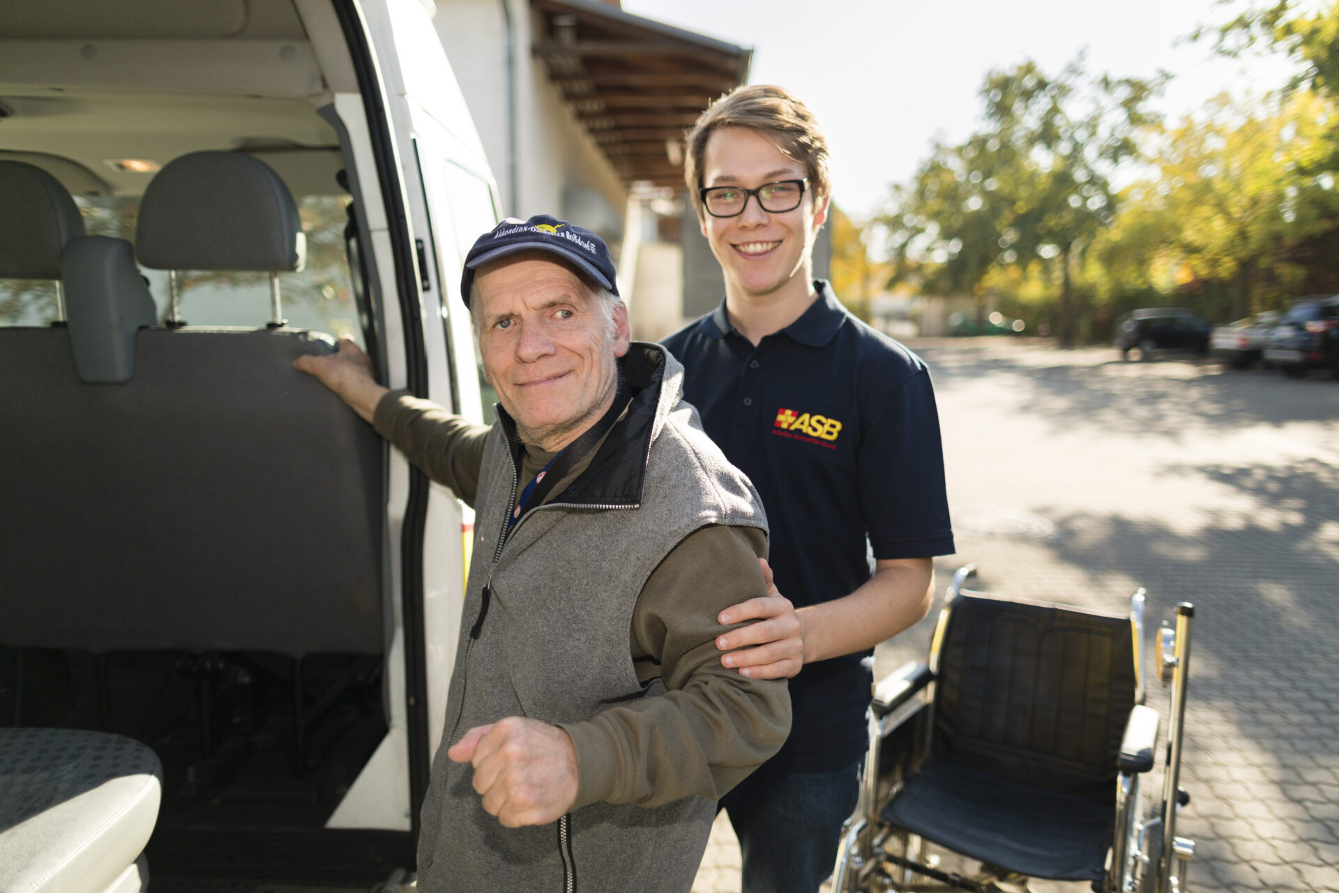 Ein junger Praktikant hilft einem Senior in einen Kleintransporter.