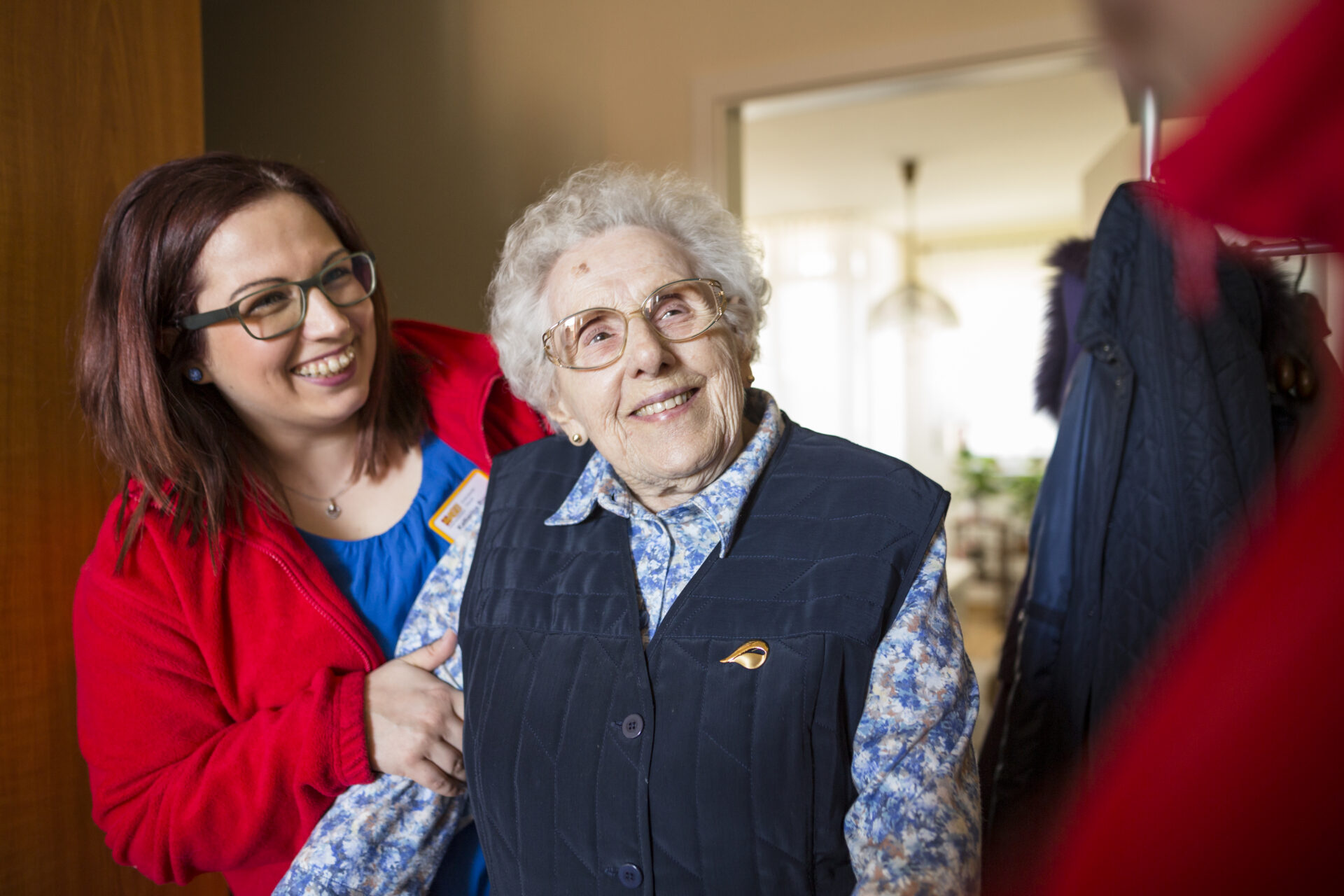 Eine Seniorin und ihre ambulante Pflegekraft lächeln in die Kamera.