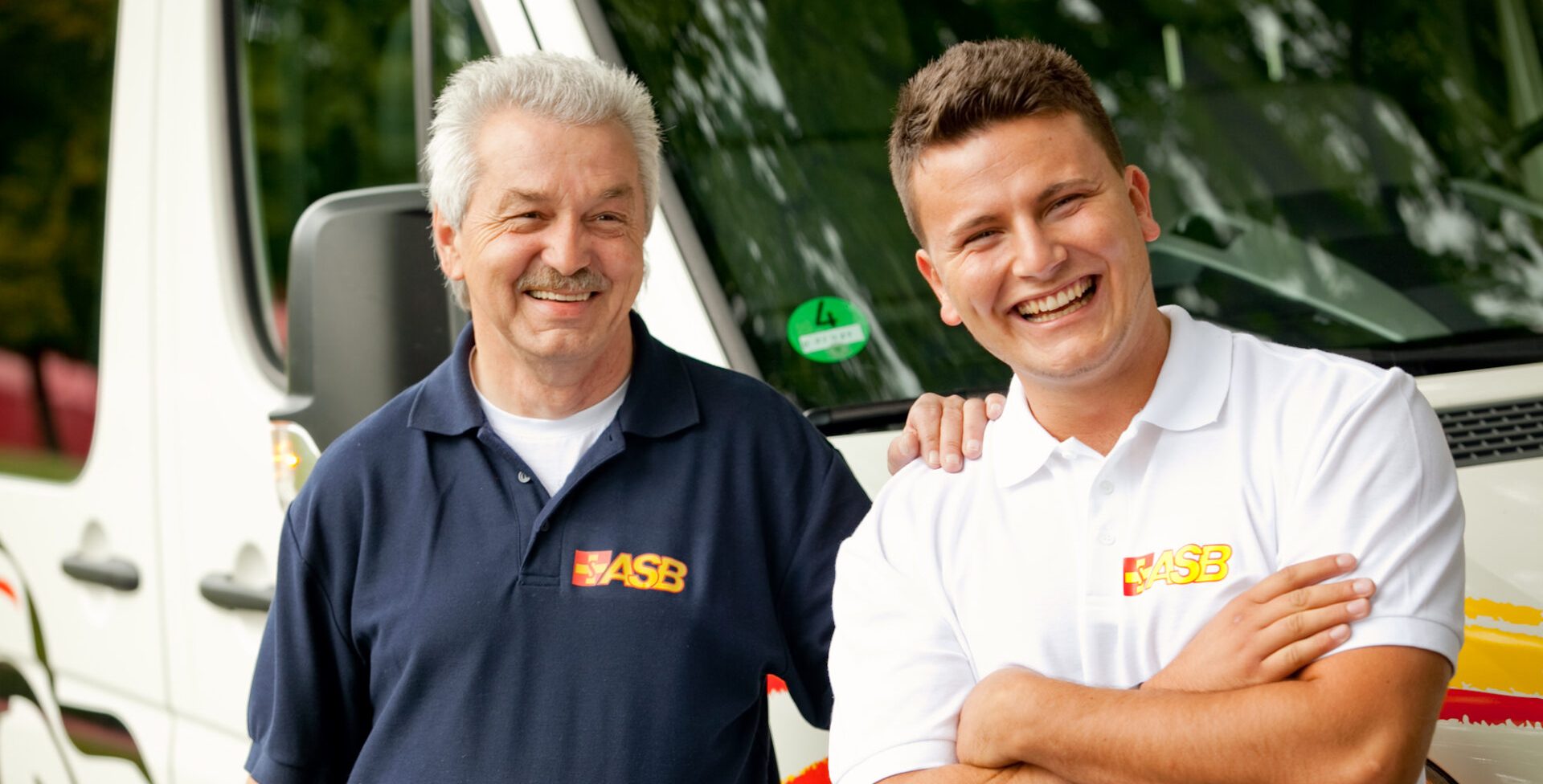 Zwei männliche Fahrer stehen vor einem Kleinbus.