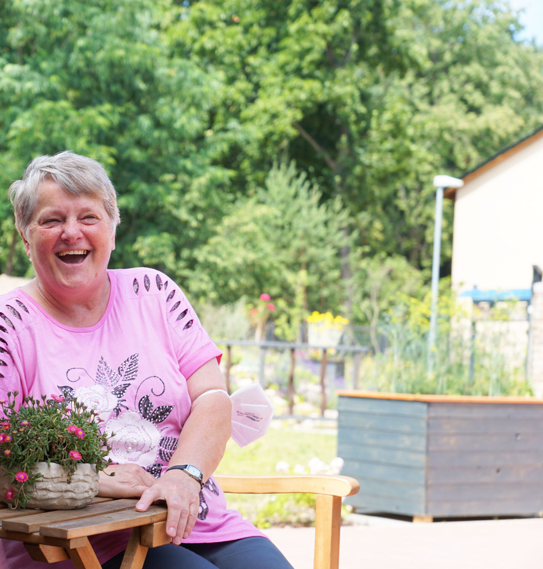 Eine Frau sitzt auf einer Terrasse und lacht.
