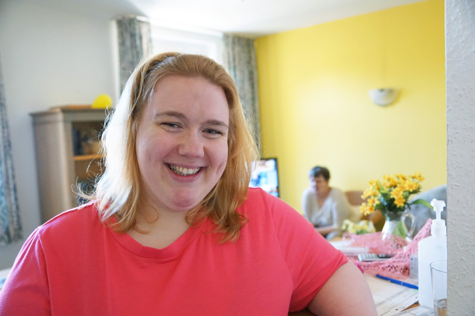 Eine junge Frau schaut lächelnd in die Kamera.